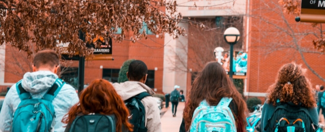 A group of diverse students walking together along a sidewalk, engaged in conversation and enjoying their time outdoors.